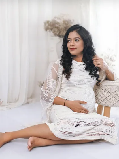 A relaxed, seated portrait on the floor. The addition of a lace shrug adds texture and detail to her outfit in this bohemian inspired white studio setup.