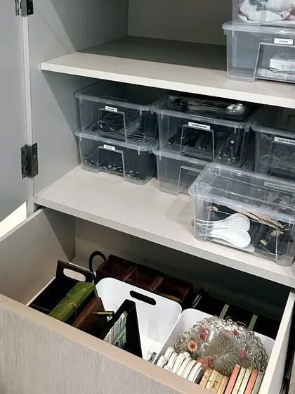 This cabinet uses clear, stackable bins with labels to organize cutlery and other dining essentials. The pull-out drawer below contains caddies for even more compartmentalized storage.