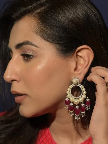 A pair of traditional chandbali earrings, featuring rich red gemstones and lustrous pearls. These are designed to add a touch of royal elegance to any festive or bridal ensemble.