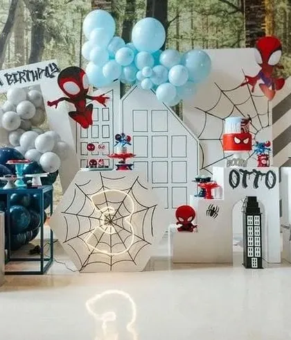 A cool Spiderman-themed party setup with city skyline backdrops, spiderweb details, and character cutouts.