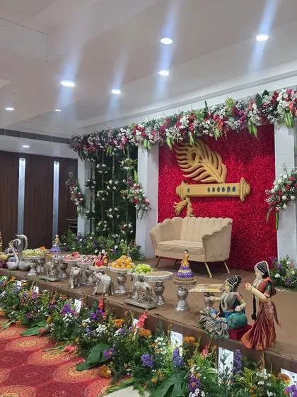 An angled shot of the Krishna flute stage, highlighting the surrounding greenery and offering table.
