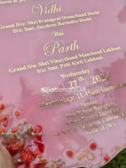 A close-up of the text on the pink resin wedding invitation. The golden metal sticker provides a crisp and elegant look against the pink background.
