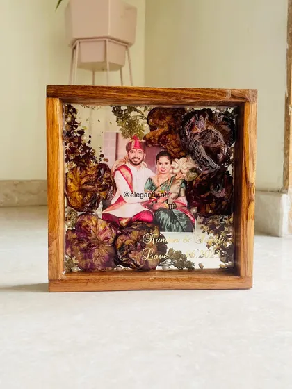 A simple yet elegant 8-inch teakwood frame preserving a couple's wedding garland. The focus is entirely on the beauty of the flowers and the couple's photo.