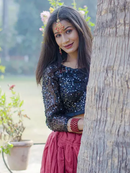 An outdoor fashion-style photoshoot, using natural elements like a tree trunk to create a playful and engaging portrait.