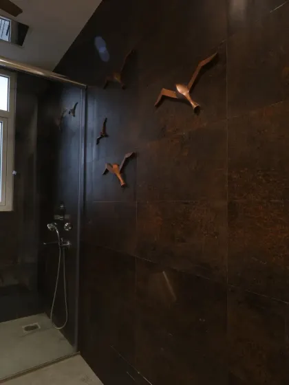 Metal bird elements on the wall add a whimsical touch to the shower area, continuing the room's modern-meets-whimsical theme.