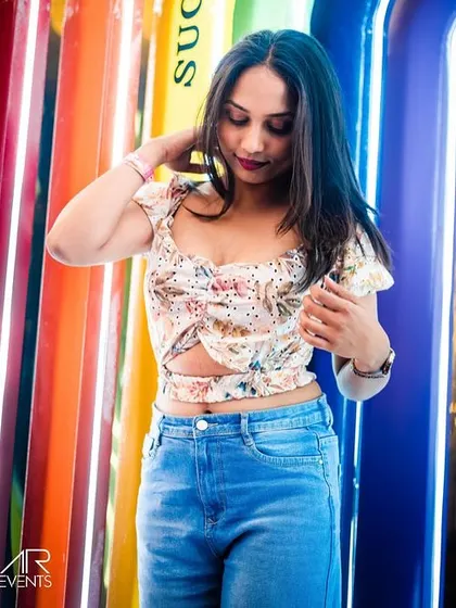 A stylish guest posing against the colorful, illuminated surfboards at Sugar Factory. The venue's unique decor provides a great backdrop for photos.