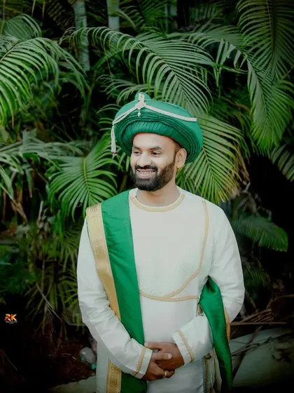 A candid shot of the groom, smiling as he looks away from the camera. Dressed in his traditional wedding kurta and turban, he looks relaxed and happy.