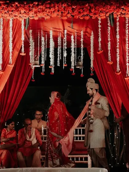 A wide shot of the pheras. The couple circles the sacred fire under a magnificent red mandap, a classic and essential moment of a Hindu wedding.
