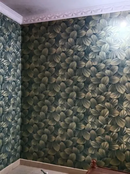 A dense, dark wallpaper with overlapping leaves creates a rich and dramatic effect. This bold pattern is perfect for an accent wall in a bedroom or study, adding a touch of moody sophistication.