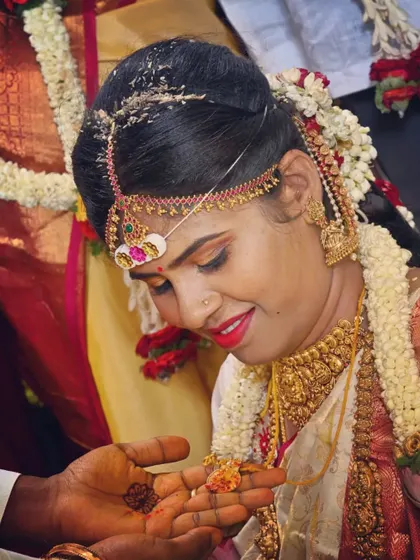 A close-up during a wedding ritual, showing the intricate details of the bride's makeup. The look includes traditional elements like the bindi and perfectly defined eyes, designed to last through the ceremony.