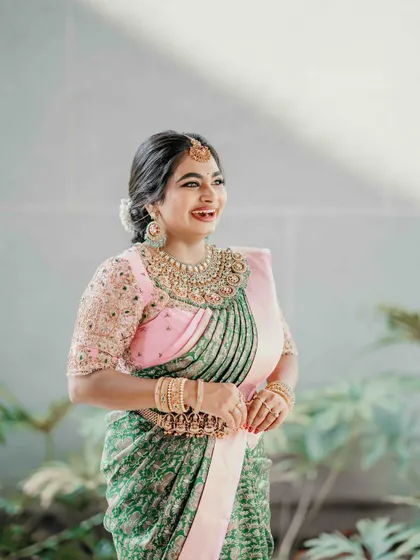 A radiant client in her custom half-saree. The pink embroidered blouse contrasts beautifully with the green patterned skirt, creating a look that is both traditional and joyful.