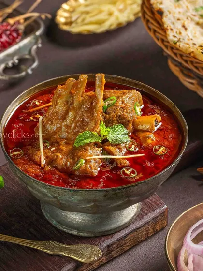 A rich and aromatic Mughlai mutton curry, photographed with dark, intense lighting to bring out the deep colors and textures of this traditional North Indian dish.