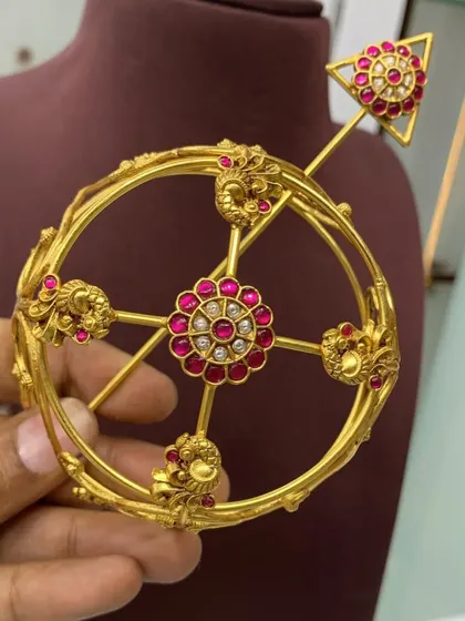 This angle shows the top view of the red stone bun cover, with its central floral motif and surrounding peacock designs. A beautiful piece for any bride.