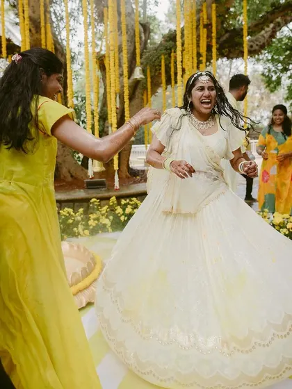 The bride dances with joy during her Haldi ceremony, surrounded by a beautiful decor of yellow flowers.