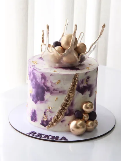 This 60th birthday cake features a violet marbled ganache finish, accented with gold leaf and an isomalt splash topper. It's a great example of combining color and modern decorative elements.