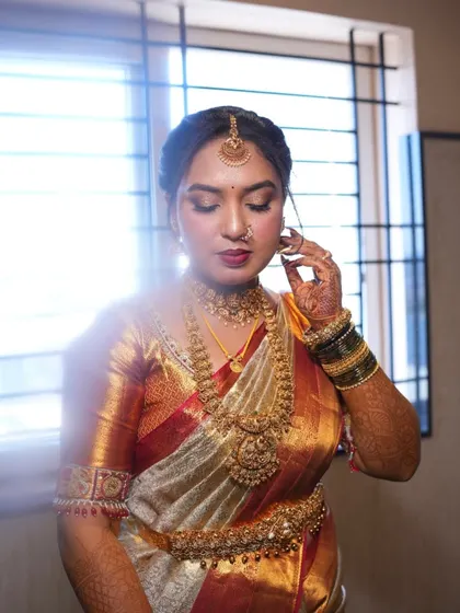 A full view of this bride's stunning muhurtham look. The makeup is designed to harmonize with her rich silk saree and heavy temple jewelry, creating a cohesive and regal appearance.