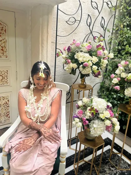 A happy bride adorned with floral jewelry, showing her completed mehndi.