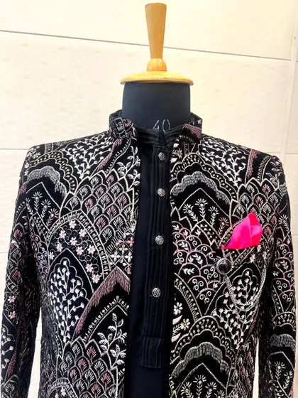 A close-up of the intricately embroidered Indo-Western jacket. The detail shows the fine craftsmanship and the blend of colors in the pattern.