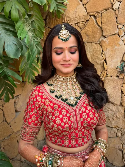 A close-up on the eye makeup, showing the beautiful pink and brown tones that complement her red lehenga. The look is soft, romantic, and glamorous.