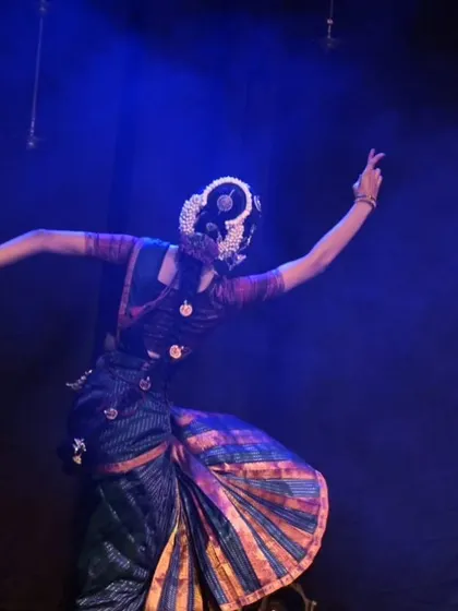 A dynamic pose showing the dancer's back, highlighting the intricate hair ornamentation and the flow of the costume during a swirling movement.