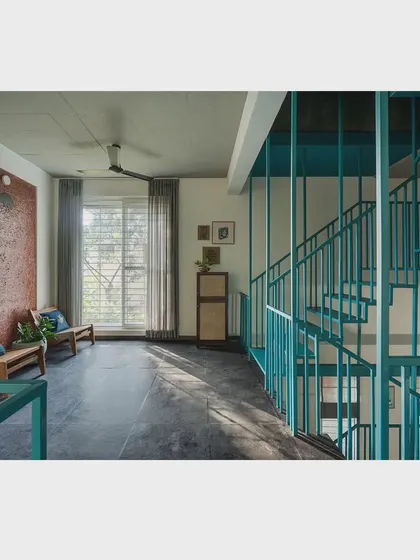 A quiet seating nook on the upper floor, overlooking the levels below. The large window allows for natural light, making it a perfect spot for morning tea while enjoying the shadow patterns cast by the staircase.