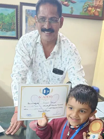 Even our youngest players are champions. A young boy smiles brightly as he receives his medal and certificate for participating in the academy tournament.