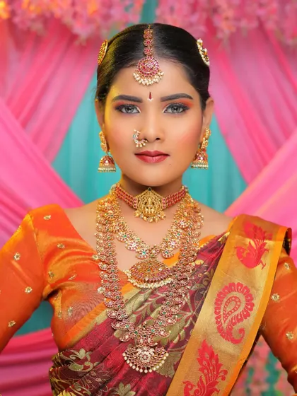 A close-up portrait of the bride. The temple choker with the goddess motif and the matching jhumkas are the highlights of this traditional set.
