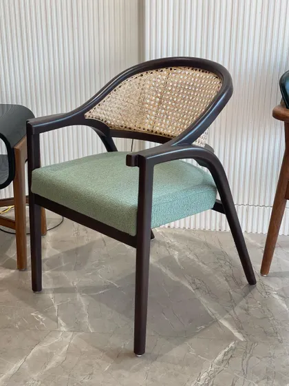 A side profile of the cane-back dining chair. This view shows off the graceful curve of the backrest and the sturdy construction of the solid wood frame.