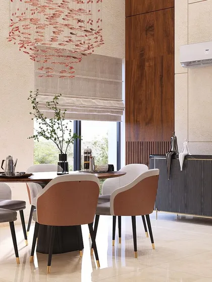 This dining area in a double-height space at Nirvana Country feels grand and airy. The round table encourages conversation, while the custom dark wood sideboard provides ample storage for dinnerware.