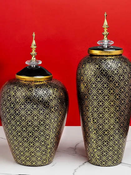 These black and gold ceramic jars showcase a delicate, Moroccan-inspired trellis pattern. The crystal-topped lids add a final touch of elegance to these beautiful decorative pieces.