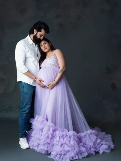 We love capturing the bond between expecting parents. This full-length shot shows the couple in a tender embrace, highlighting the gorgeous ruffled train of the lavender gown.