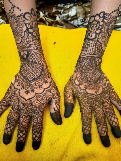 A traditional Indian bridal design with heavy, intricate patterns covering the entire hand. The dark-tipped fingers and detailed work are classic elements for a bride's mehendi.