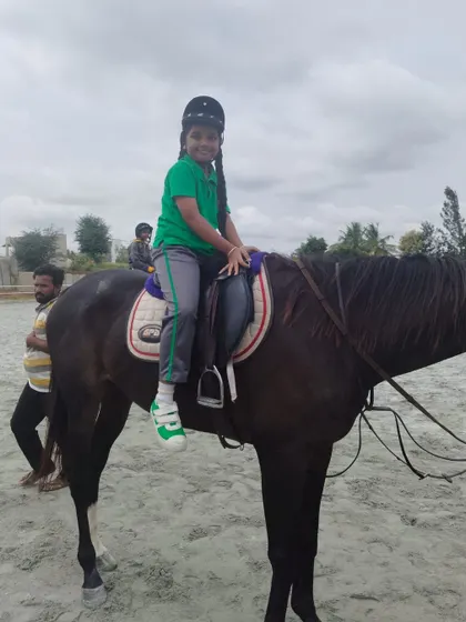 A young rider smiles for the camera, clearly enjoying the fun and engaging workout that horse riding provides.