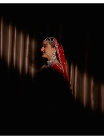 An artistic bridal portrait using strong directional light to create a dramatic play of light and shadow. This technique highlights the bride's profile and creates a moody, cinematic feel.