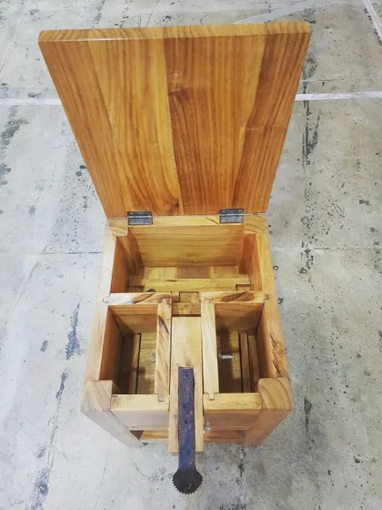 An overhead view of the coconut grater, showing the internal compartments for collecting grated coconut and the sturdy mounting of the grater blade.