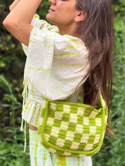 A lifestyle shot of our popular checkerboard crochet bag, showing how it can elevate a simple summer outfit.