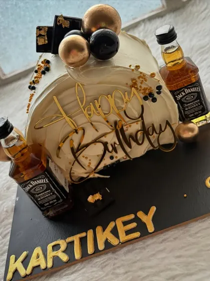 A top-forward cake for a Jack Daniel's fan. This modern design is decorated with mini liquor bottles, gold spheres, and chocolate accents.
