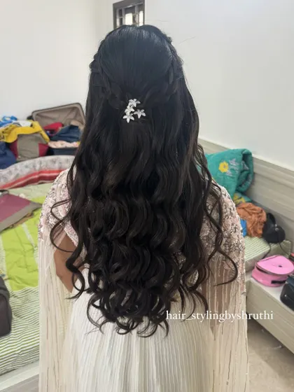 A simple half-up style with natural-looking waves, secured with a single sparkling hair clip. This is a great example of an understated yet elegant hairstyle for a wedding guest.