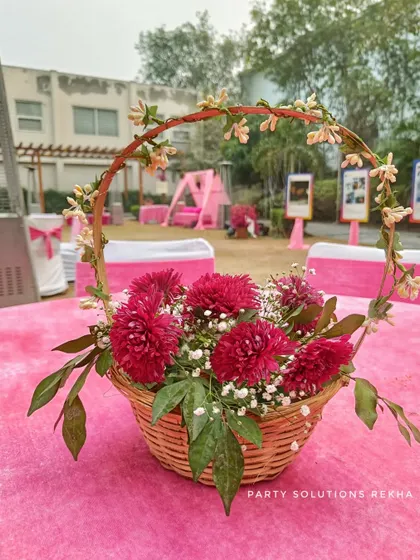A beautiful floral centerpiece in a wicker basket, perfect for a rustic or bohemian-themed event. These small details on guest tables help tie the entire decor theme together.