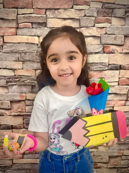 A happy student holds up the pencil-shaped box and clay keychain she made for her teacher. Our Teacher's Day workshop is all about creating thoughtful, handmade gifts from the heart.