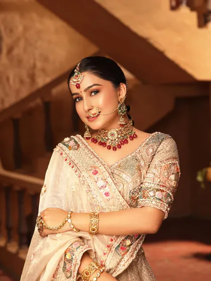 A bridal look is not just about red. This close-up shows the delicate, multi-color threadwork on one of my elegant beige designer lehengas. Paired with a red-beaded choker, it’s a perfect example of a modern yet traditional reception look.