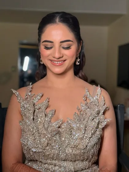 A beautiful portrait of a bride ready for her reception or cocktail party. The makeup is soft and glamorous, with a focus on glowing skin and shimmery eyes.
