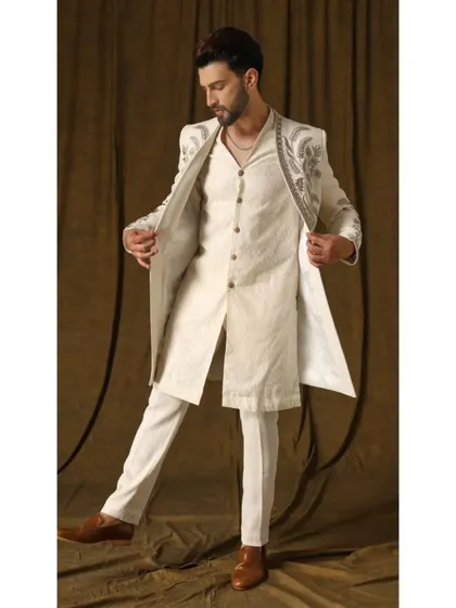 A dynamic view of the 'Pragyan' shrug set, showing how the open-front jacket moves with the wearer. The ivory ensemble with its detailed embroidery is designed for both comfort and a grand entrance.