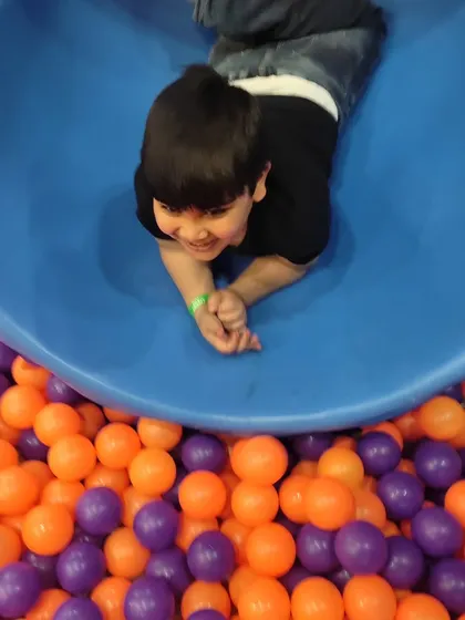 A cheerful face peeking out from the slide before plunging into the ball pit. This is the kind of pure, simple fun we love to provide.
