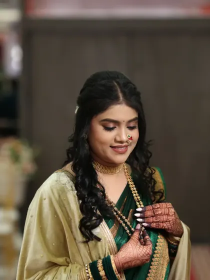A candid moment of the bride adjusting her necklace. Her makeup is soft and flawless, perfect for her engagement day.