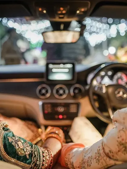 The color version of the couple's post-wedding car ride. This candid shot captures their conversation and shared look, with the bokeh of the wedding lights in the background signaling the end of a beautiful day.