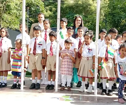 A group of students stands by the flagpole with our esteemed guests, ready for the Independence Day ceremony.
