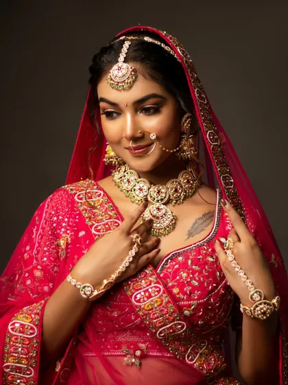 A mid-body shot of the bride in her stunning red lehenga, showing the intricate embroidery and jewellery.