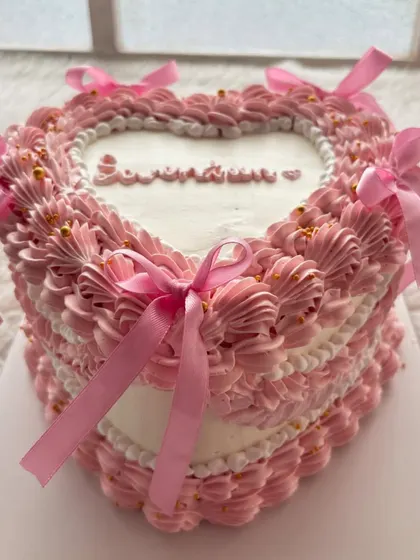 A vintage heart-shaped cake with pink ribbons and delicate piping. This style is making a huge comeback and is perfect for birthdays or anniversaries.