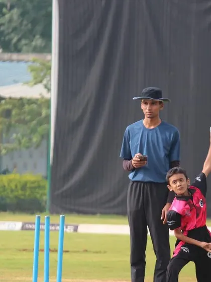 A young boy practices his bowling action under the guidance of a senior player, a great example of peer-to-peer learning at our academy.